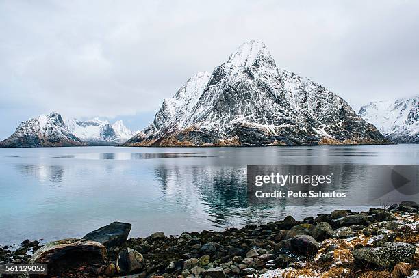 view of snow capped mountain and rocky coastline, reine, lofoten, norway - moskenesoya stock pictures, royalty-free photos & images