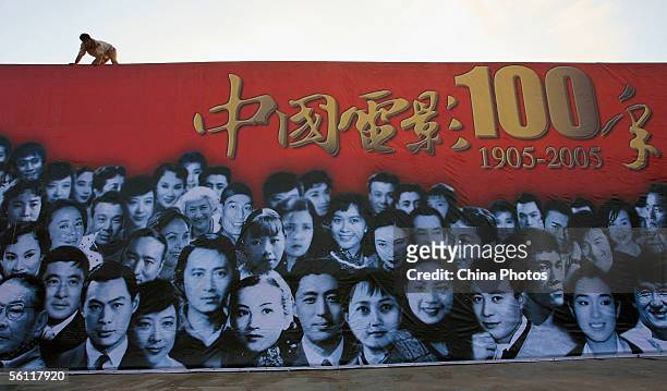 Worker installs a billboard featuring Chinese famous actors and actresses to mark the centennial of Chinese film at the Deer Looking Back Square on...