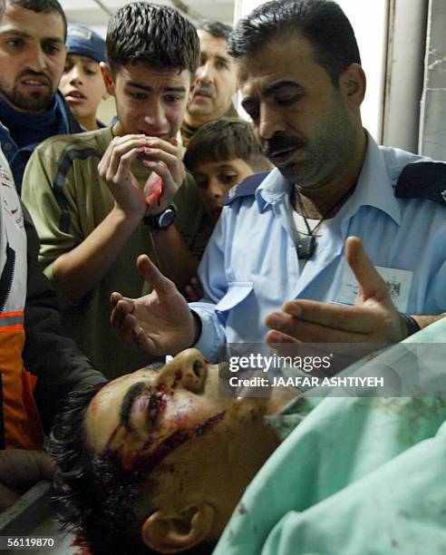 Palestinian policeman recites a prayer for the dead as unidentified relatives look at the body of Mohammed Abu Salha at the morgue of a hospital in...