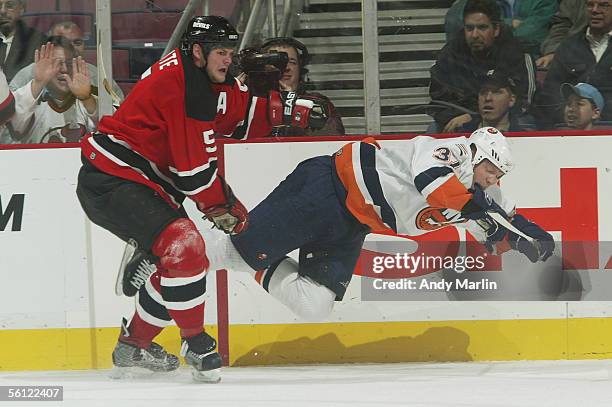 Defenseman Colin White of the New Jersey Devils checks right wing Mark Parrish of the New York Islanders through the air at Continental Airlines...