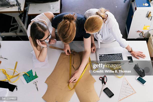 three women fashion designers working with sewing - design laptop woman stock-fotos und bilder