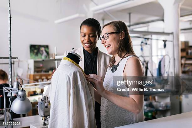 two female dressmakers working in studio - industrie de la mode photos et images de collection