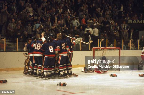 Canadian pro hockey player J.P. Parise of the New York Islanders is mobbed by his teammates after his overtime goal helped them beat their rivals the...