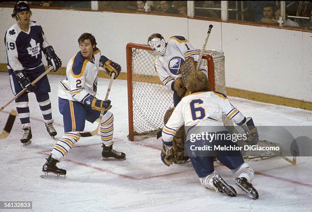 Professional hockey player Tim Horton of the Buffalo Sabres guards his net with fellow defenseman Jim Schoenfeld as Maple Leaf Paul Henderson looks...