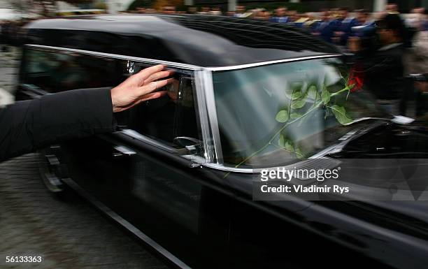 Red roses are thrown onto the hearse containing Aenne Burda from people lining the funeral route after the funeral service on November 10, 2005 in...