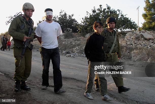 Israeli soldiers arrest two Palestinian youths following a stone-throwing incident during a demonstration marking the first anniversary of the death...