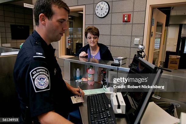 Customs and Border Protection officer checks the passport of a European tourist on the Rainbow Bridge on September 20, 2005 in Niagara Falls,...