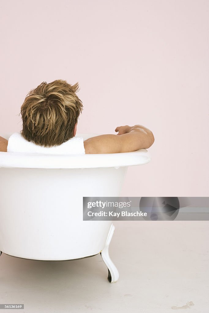 Man lying in bathtub, rear view