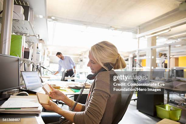 businesswoman using phone in modern office - teléfono con cable fotografías e imágenes de stock