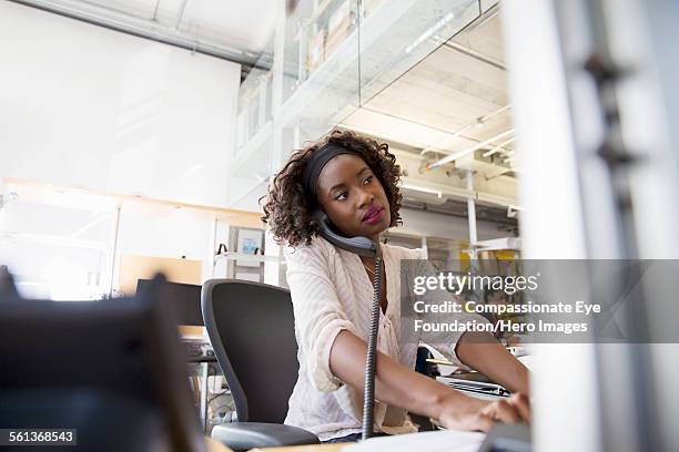 businesswoman using phone while working in office - landline phone woman stock pictures, royalty-free photos & images