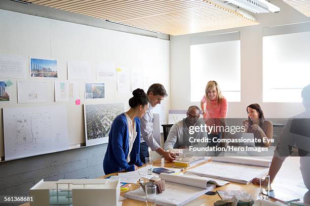 business people discussing blue prints in office - multi ethnic business people having discussion at table in board room stock pictures, royalty-free photos & images