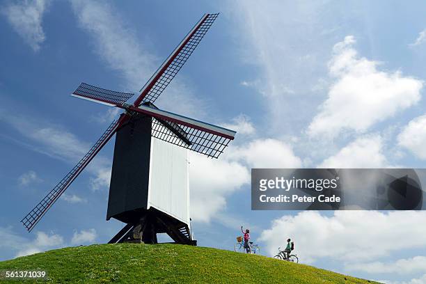 couple on bikes looking at a windmill. - west vlaanderen stockfoto's en -beelden