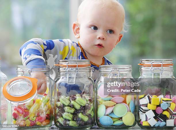 little boy taking sweet from sweet pots - confectionery stock pictures, royalty-free photos & images