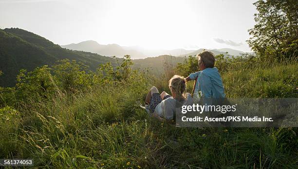 couple relax in meadow to look out across hills - lying on grass stock-fotos und bilder