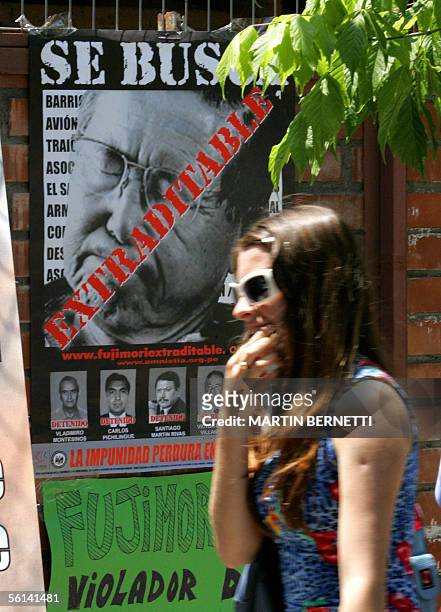 Una mujer pasa frente a un afiche alusivo al ex presidente peruano Alberto Fujimori , frente a la Escuela de Gendarmeria en Santiago el 11 de...