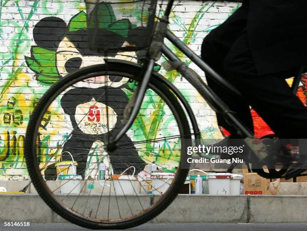 Cyclist rides past graffiti of the Beijing 2008 Olympic mascots on the wall November 12, 2005 in Beijing, China. Beijing Olympic organizers chose...