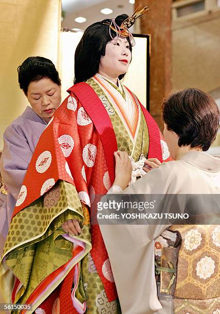 Kimono seamstresses put an ancient Japanese formal court ensemble called a junihitoe on a model for a kimono show at Tokyo's Mitsukoshi department...