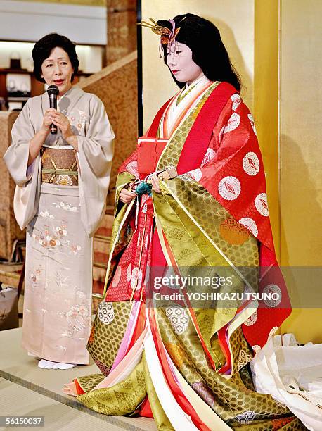 Kimono seamstress Mikami Kazuko explains the details of an ancient Japanese formal court ensemble called a junihitoe on a model for a kimono show at...