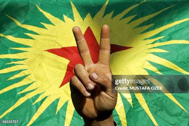 Demonstrator flashes a V-sign before outlawed PKK flag, 13 November 2005, during the "democracy and peace" demonstration organised by local...