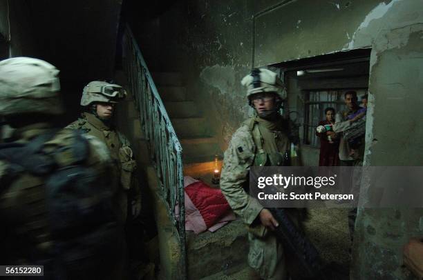 An Iraqi family holding two children wait in their kitchen as U.S. Marines of Fox Company, 2nd Battalion 6th Marine Regiment, search their house in...