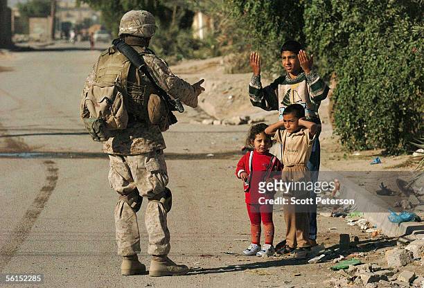 Marine of Fox Company, 2nd Battalion 6th Marine Regiment, gestures with children while patrolling the streets area November 13, 2005 in Fallujah,...