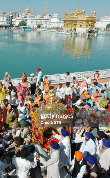 Indian Sikh devotees carry the Guru Granth Sahib, the holy book of the Sikh religion, in a procession at the Golden Temple in Amritsar, 14 November...