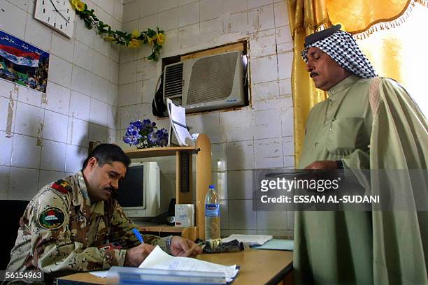 An senior Iraqi army officer completes the documents of a former Iraqi soldier at a military office in the southern city of Basra 14 November 2005....