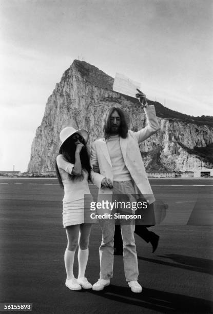 Yoko Ono & Yoko Ono, both dressed in white, pose with their marriage certificate after their wedding in Gibraltar, 20th March 1969.