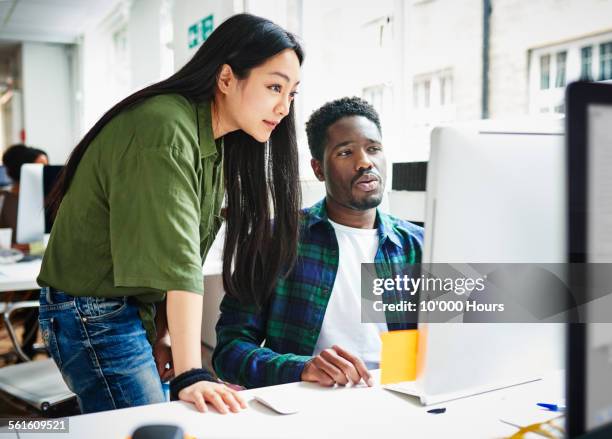 colleagues in office looking at a computer screen - co workers looking at computer stock pictures, royalty-free photos & images