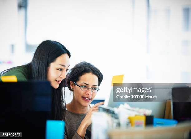 businesswomen at computer screen in startup office - sguardo e complicità foto e immagini stock