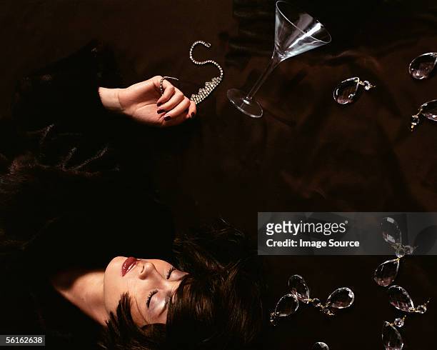 woman lying on floor with necklace and cocktail glass - diamond necklace stock pictures, royalty-free photos & images