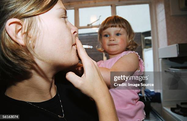 woman smoking near baby - mother and daughter smoking - fotografias e filmes do acervo