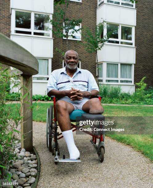 man in wheelchair in garden - amputé photos et images de collection