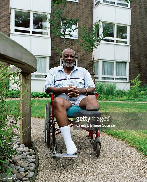 man in wheelchair in garden - amputatie stockfoto's en -beelden