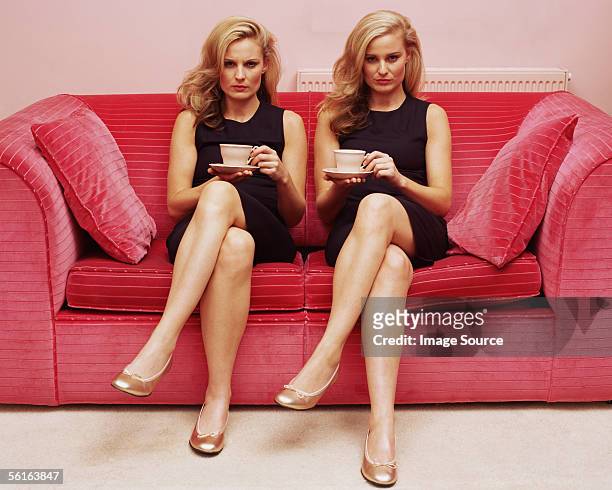 two women holding cups of tea - erwachsene imitieren stock-fotos und bilder