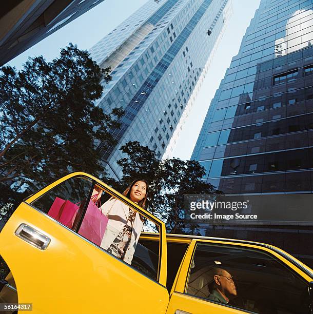 woman leaving taxicab with shopping bags - yellow taxi fotografías e imágenes de stock
