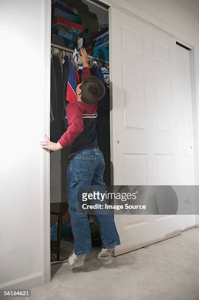 boy trying to reach shelf in wardrobe - childrens closet stock pictures, royalty-free photos & images