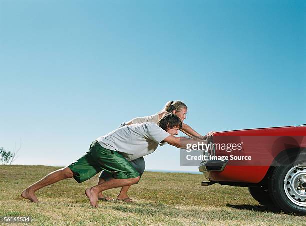 couple pushing car - young couple red sunny stock pictures, royalty-free photos & images