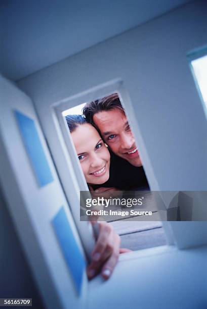 couple looking through door of doll house - looking through a doll house photos et images de collection