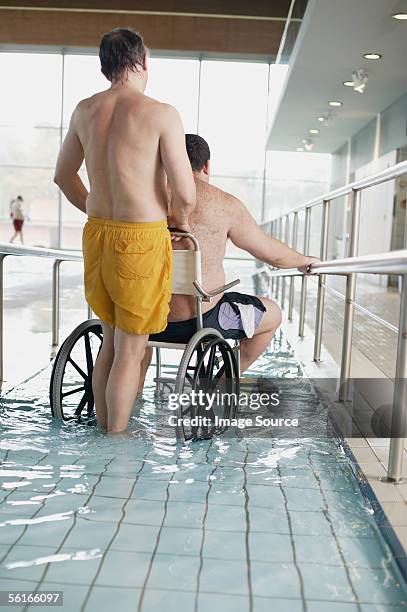 two men entering swimming pool - rollstuhl schieben stock-fotos und bilder