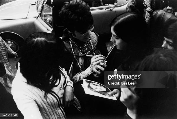 John Lennon of the Beatles signs autographs for fans as he arrives for rehearsals at the EMI studios in London, 22nd June 1966.