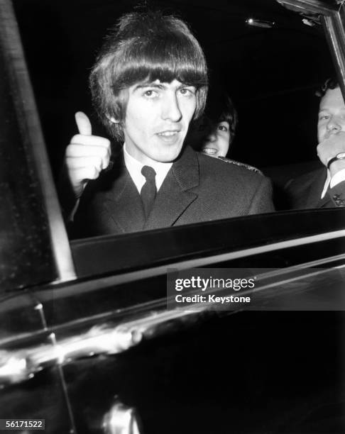 George Harrison of the Beatles gives a 'thumbs up' sign from his car window, whilst on his way to Buckingham Palace to collect an MBE, 26th October...