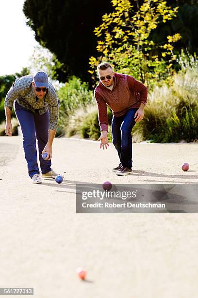 two men playing bocci ball together in the park. - bocce ball stock pictures, royalty-free photos & images