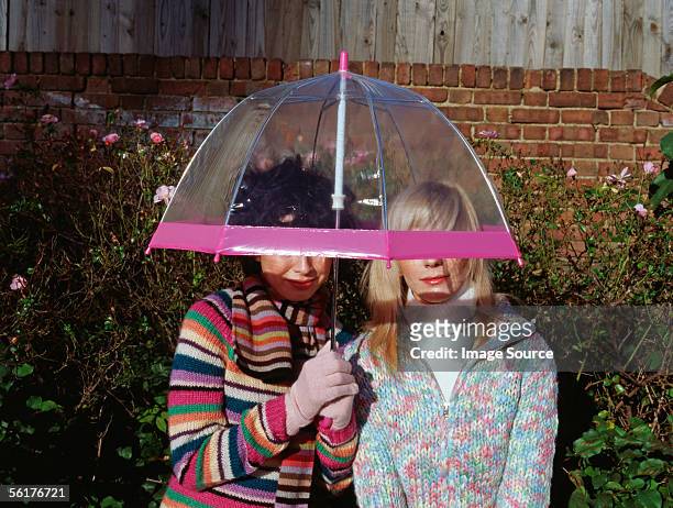 two friends under an umbrella - sharing umbrella stock pictures, royalty-free photos & images