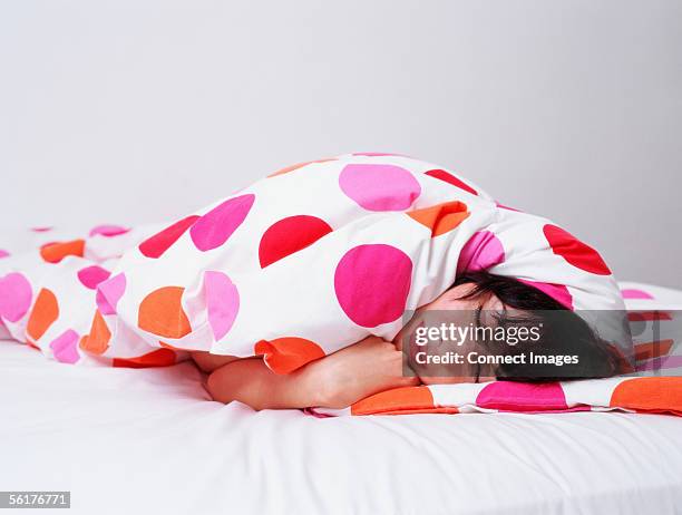 woman sleeping wrapped up in duvet - tied to bed stockfoto's en -beelden