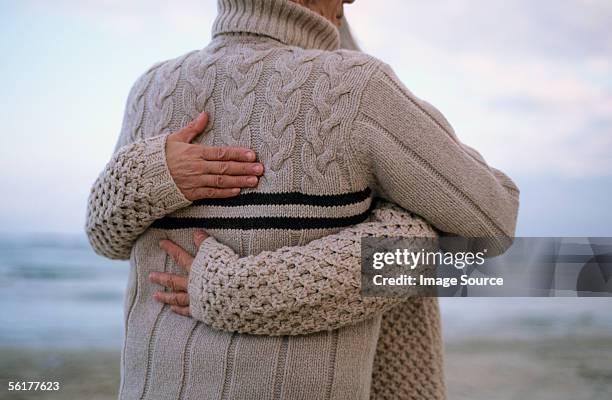 rear view of couple hugging on beach - older couple hugging on beach stock pictures, royalty-free photos & images