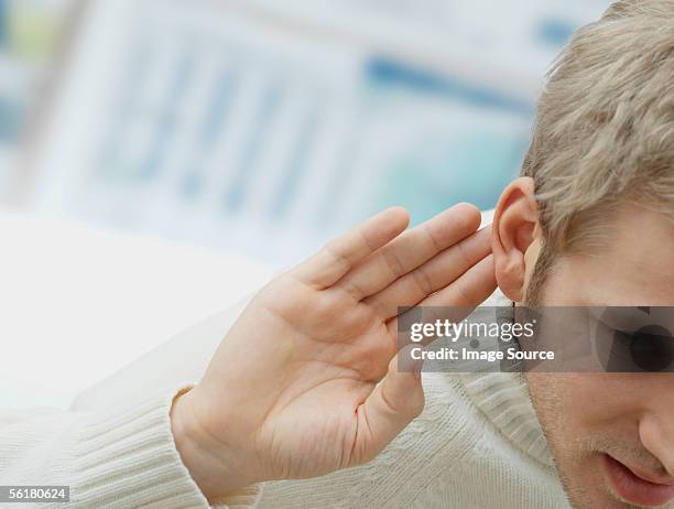 man putting his hand to his ear - deafness stock-fotos und bilder