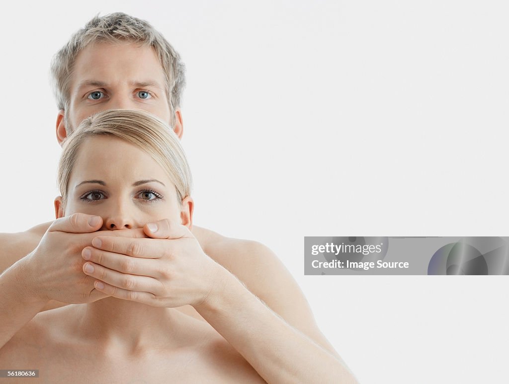 Man covering woman's mouth