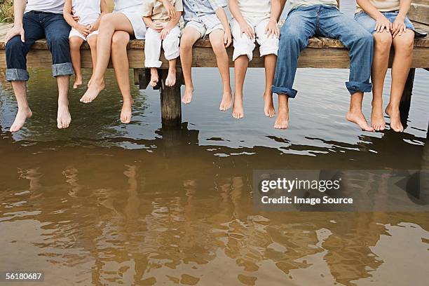 menschen im wind baumelnden ihre füße auf einem pier - family feet stock-fotos und bilder