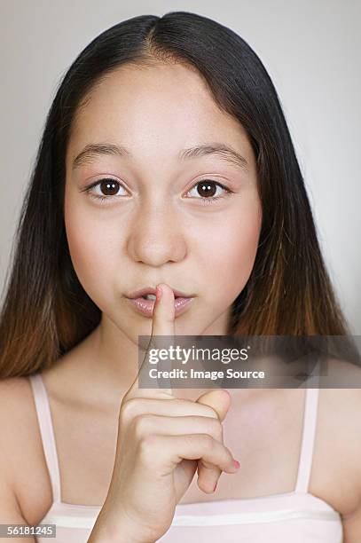 girl putting a finger to her lips - kid putting finger in mouth stock-fotos und bilder